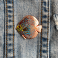 Discus fish hard enamel pin. Blue discus with yellow, orange, and red lines.